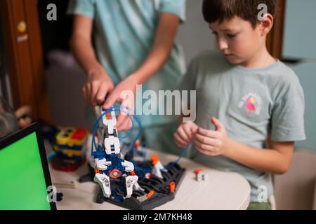 Children learning repairing getting lesson control robot arm, robotic machine arm in home workshop, technology future science education. Stock Photo