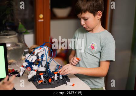 Children learning repairing getting lesson control robot arm, robotic machine arm in home workshop, technology future science education. Stock Photo