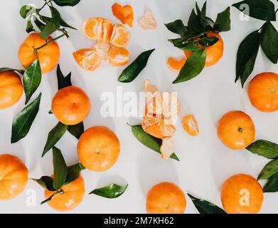 Composition from fresh ripe tangerines and leaves on white background, flat lay. Citrus fruit top view Stock Photo