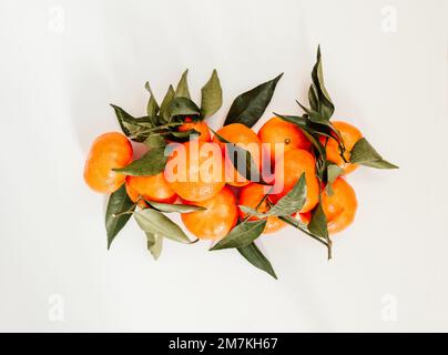 Composition from fresh ripe tangerines and leaves on white background, flat lay. Citrus fruit top view Stock Photo