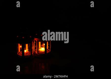 Ornamental Arabic lantern with burning candle glowing at night. Festive greeting card, invitation for Muslim holy month Ramadan Kareem. Dark backgroun Stock Photo