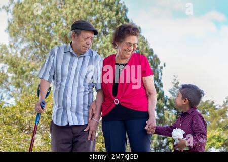 Happy elderly couple holding hands with their great grandchild. Elderly spending time with their great-grandchild. Stock Photo