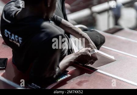 A black man sitting on the stairs with a book in his hands on the blurred background Stock Photo