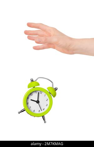 Hand dropping lime green metal alarm clock isolated on white background. Concept of time. On the clock face, it's five minutes to nine in the morning. Stock Photo