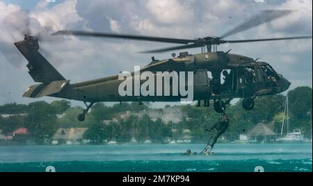 A Dutch Marine with the Netherlands Marine Corps climbs a ladder attached to a U.S. Army Sikorsky UH-60 Black Hawk helicopter during helocast extraction drills during exercise Tradewinds 2022 (TW22), at Bacalar lagoon, Mexico, May 11, 2022. TW22 is a U.S. Southern Command-sponsored Caribbean-focused multi-dimensional exercise conducted in the ground, air, sea, and cyber domains, designed to provide participating nations opportunities to conduct joint, combined, and interagency training focused on increasing regional cooperation and interoperability in complex multinational security operations. Stock Photo