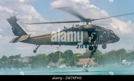 A Dutch Marine with the Netherlands Marine Corps climbs a ladder attached to a U.S. Army Sikorsky UH-60 Black Hawk helicopter during helocast extraction drills during exercise Tradewinds 2022 (TW22), at Bacalar lagoon, Mexico, May 11, 2022. TW22 is a U.S. Southern Command-sponsored Caribbean-focused multi-dimensional exercise conducted in the ground, air, sea, and cyber domains, designed to provide participating nations opportunities to conduct joint, combined, and interagency training focused on increasing regional cooperation and interoperability in complex multinational security operations. Stock Photo