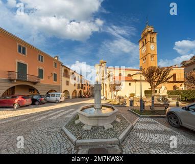 Peveragno, Cuneo, Italy - January 09; 2023: stone fountain in Piazza Santa Maria with the parish church of Santa Maria and the bell tower Stock Photo