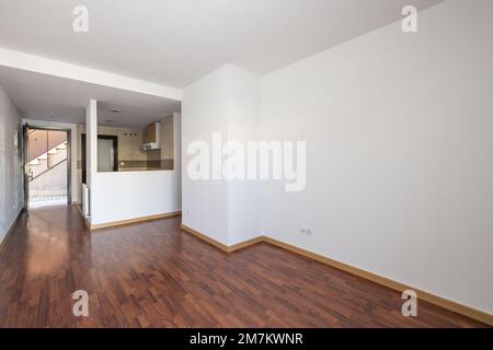 An empty loft-style apartment with a semi-open kitchen with serving hatch and reddish jatoba flooring Stock Photo