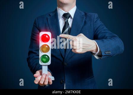 Businessman holding a traffic light with red light on. Business concept Stock Photo