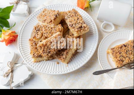 Hazelnut cake with caramelized nut topping. Served sliced on a white plate with easter decoration on white background Stock Photo