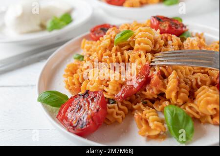 Pasta with tomato mozzarella sauce, parmesan cheese and basil on a plate Stock Photo
