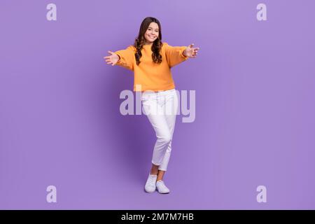 Full length photo of sweet friendly girl dressed orange sweatshirt open arms ready hug you isolated purple color background Stock Photo