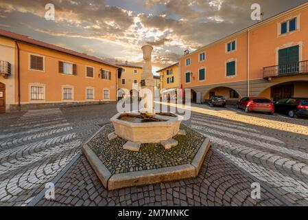 Peveragno, Cuneo, Italy - January 09; 2023: marble fountain with drinking trough on cobblestones in Piazza Santa Maria with ancient palaces decorati w Stock Photo