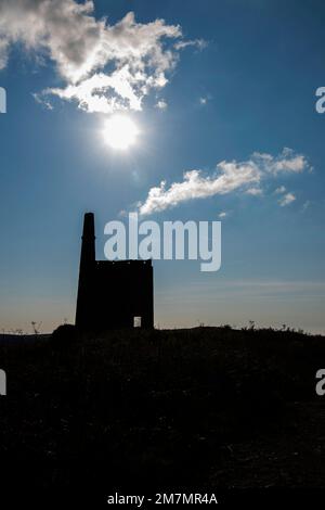 Greenburrow Engine house at Ding Dong tin mine silhouetted against blue sky and sun Stock Photo