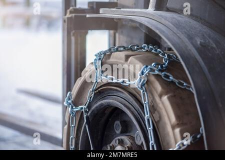 Cargo loader in winter on snow. The loader ride on snow with chains on the wheels to reduce slippage and spin. Driving safety in winter conditions Stock Photo