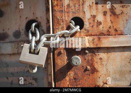 Italy, Veneto, rusty iron door closed by chain and padlock Stock Photo