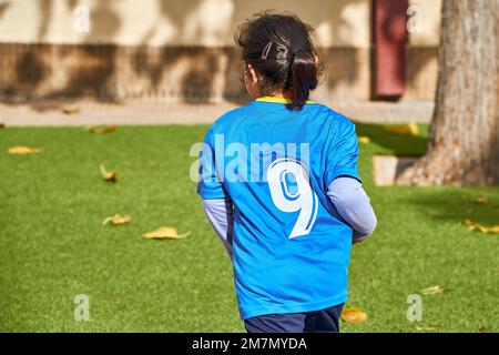 latin girl football player in a sport suit running on a green soccer field Stock Photo