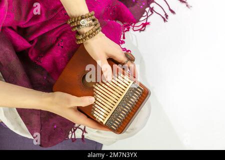 Woman holding kalimba in her hands and playing. Concept of Relaxing at home, Me time and self care and sound meditation. Woman enjoy the melodious sou Stock Photo