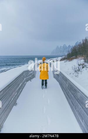 Young woman with yellow raincoat in Norway, Lofoten, fishing village Stock Photo