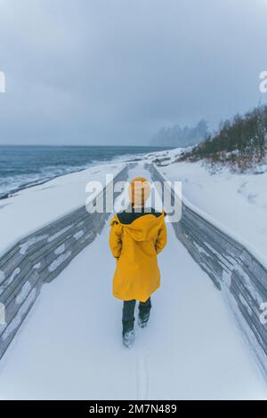 Young woman with yellow raincoat in Norway, Lofoten, fishing village Stock Photo