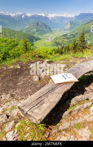 A wooden bench and trekking register in front of the Vodnikov lookout point with view of Bohinj lake and valley. Bohinjska Bistrica, Slovenia, Europe. Stock Photo