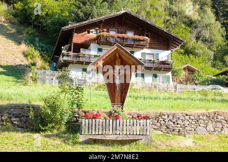 Marterl in front of South Tyrolean farmhouse on steep slope at the edge of the forest Stock Photo
