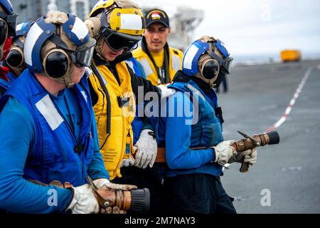 220511-N-DW158-1074 PACIFIC OCEAN (May 11, 2022) Sailors man firefighting hoses in response to a simulated fire during a mass casualty drill on flight deck of the U.S. Navy’s only forward-deployed aircraft carrier USS Ronald Reagan (CVN 76). The drills are designed to simulate a mass casualty event where firefighting and medical response teams train in unison to maintain mission readiness. Ronald Reagan, the flagship of Carrier Strike Group 5, provides a combat-ready force that protects and defends the United States, and supports alliances, partnerships and collective maritime interests in the Stock Photo
