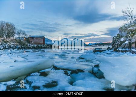 Small old harbor in fjord in North Norge, Norway, frozen and icy surface, fjord landscape with sea and boat Stock Photo