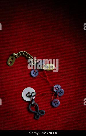 Sewing utensils strung on a red thread Stock Photo