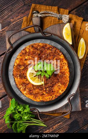 Traditional delicious Turkish foods lahmacun with mince lamb meat in steel tray. Wooden background. Top view Stock Photo