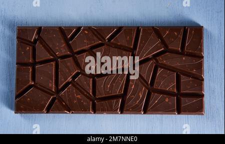 Milk chocolate with hazelnuts and peanuts crushed inside on a blue wooden board Stock Photo