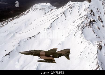 An air-to-air left side view of an RF-4C Phantom II aircraft over a snow-capped mountain. The aircraft is from the 152nd Tactical Reconnaissance Group, Nevada Air National Guard. Base: Sierra Mountains State: Nevada (NV) Country: United States Of America (USA) Stock Photo