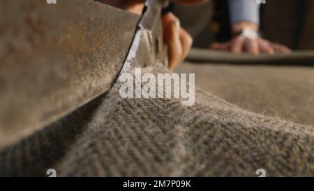 Close-up shot of tailor cutting textile according to sketch using scissors for sewing. Process of making clothes in luxury designer atelier or tailoring studio. Fashion and hand craft concept. Stock Photo
