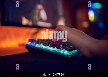 Close Up Hands Shot Showing a Gamer Pushing the Keyboard Buttons while Playing an Online Video Game. Keyboard Led Lights. Room is Dark. Stock Photo