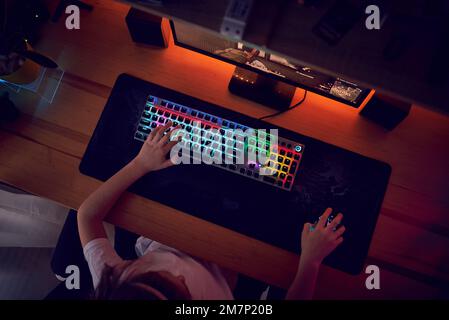 Close Up Hands Shot Showing a Gamer Pushing the Keyboard Buttons while Playing an Online Video Game. Keyboard Led Lights. Room is Dark. Stock Photo