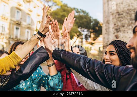 A diverse group of young people are happily high-fiving each other - close up of young adults multiracial people congratulating joining hands together Stock Photo