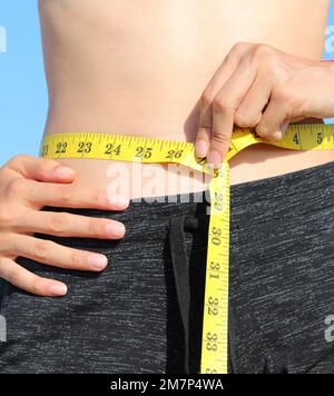 Woman Measuring Her Waist With A Yellow Measuring Tape, Isolated