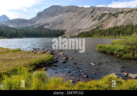 Mitchell Lake - A sunny Summer evening at Mitchell Lake, with rocky Southeast ridge of Mount Audubon rising high at shore. Indian Peaks Wilderness, CO. Stock Photo