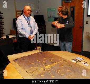 Susan Anderson (right) provides some insights to the State of Indiana flag that she is donating as an artifact to the Hampton Roads Naval Museum to Museum Educator Zach Smyers (left). The flag belonged Anderson’s father, the late Captain Walter “Jack” Deal, USN, who was the Commanding Officer of River Assault Squadron 15 during the Vietnam War. At the time, it was customary for boat captains to fly the state flag of their home state on their river assault boats during the Vietnam War. Stock Photo