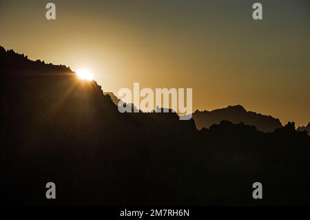 sun setting over a mountain ridge in the Sierra Nevada Mountains Stock Photo