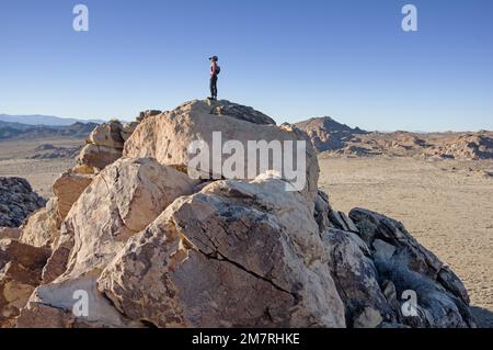 woman on a rocky mountain top in Joshua Tree National Park Stock Photo