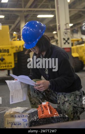 SASEBO, Japan (May 12, 2022) Logistics Specialist 2nd Class Sijia Zou, from Los Angeles, assigned to the forward-deployed amphibious assault ship USS America (LHA 6), verifies parts orders in the ship’s         vehicle stowage area. America, lead ship of the America Amphibious Ready Group, is operating in the U.S. 7th Fleet area of responsibility to enhance interoperability with allies and partners and serve as a ready response force to defend peace and stability in the Indo-Pacific region. Stock Photo