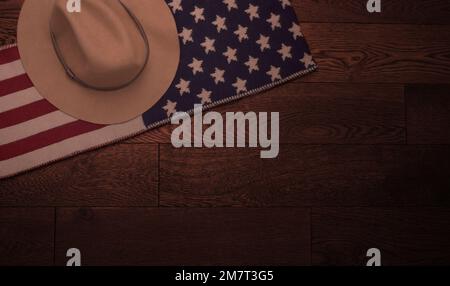 Overhead flat lay of an American flag scarf with a cowboy hat on it against a wooden background Stock Photo