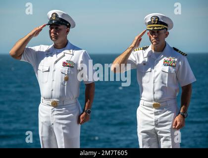 PACIFIC OCEAN (MAY 12, 2021) Capt. Aaron Taylor, commanding officer of amphibious assault ship USS Essex (LHD 2), a native of Carlsbad, California, right, and Command Master Chief Jason Ortega, command master chief of Essex, a native of San Antonio, Texas, salute during a burial at sea aboard Essex May 12, 2021. Essex is underway conducting routine operations in U.S. 3rd Fleet. Stock Photo