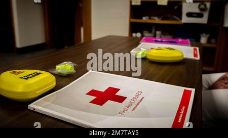 An American Red Cross first aid/cardio-pulmonary resuscitation (CPR)/automated external defibrillator (AED) participant’s manual sits on a table at Minot Air Force Base, North Dakota, May 12, 2022. The class offers training in cardio-pulmonary resuscitation (CPR) and automated external defibrillator (AED) use to resuscitate individuals in emergency situations until medical personnel arrive. Stock Photo