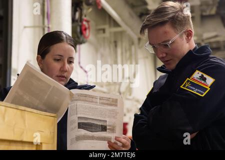 220514-N-CM110-1006 PACIFIC OCEAN (May 14, 2022) – Aerographer’s Mate 1st Class Ashley Mccown, from El Paso, Texas, left, and Aerographer’s Mate 3rd Class Chase Mischka, from Santee, California, read instructions for unboxing a buoy in the vehicle stowage area aboard amphibious assault carrier USS Tripoli (LHA 7), May 14, 2022. Tripoli is underway conducting routine operations in U.S. 7th Fleet. Stock Photo