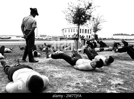 STAFF Sergeant Robert E. Brown, a drill instructor at the Aviation Officer Candidate School, walks among his class of candidates as they perform leg lifts. Base: Naval Air Station, Pensacola State: Florida (FL) Country: United States Of America (USA) Stock Photo