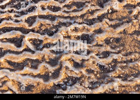 Abstract natural background, wavy relief pattern of melting coastal ice mixed with snow Stock Photo