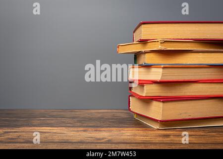 Composition with vintage old hardback books, on wooden table and gray background. stack of books. Back to school. Education. Stock Photo