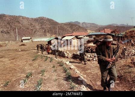 Members of Company C, 1ST Battalion, 35th Infantry, 25th Infantry Division, move along the edge of a farm village as the advancing Orange Force moves toward them, during the joint South Korean/US training Exercise TEAM SPIRIT '82. Subject Operation/Series: TEAM SPIRIT '82 Base: Cheop Yeong Country: Republic Of Korea (KOR) Stock Photo